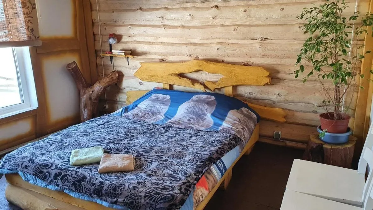 Istabiņa ar guļbaļķu sienām un divguļamo gultu ar koka galvgali